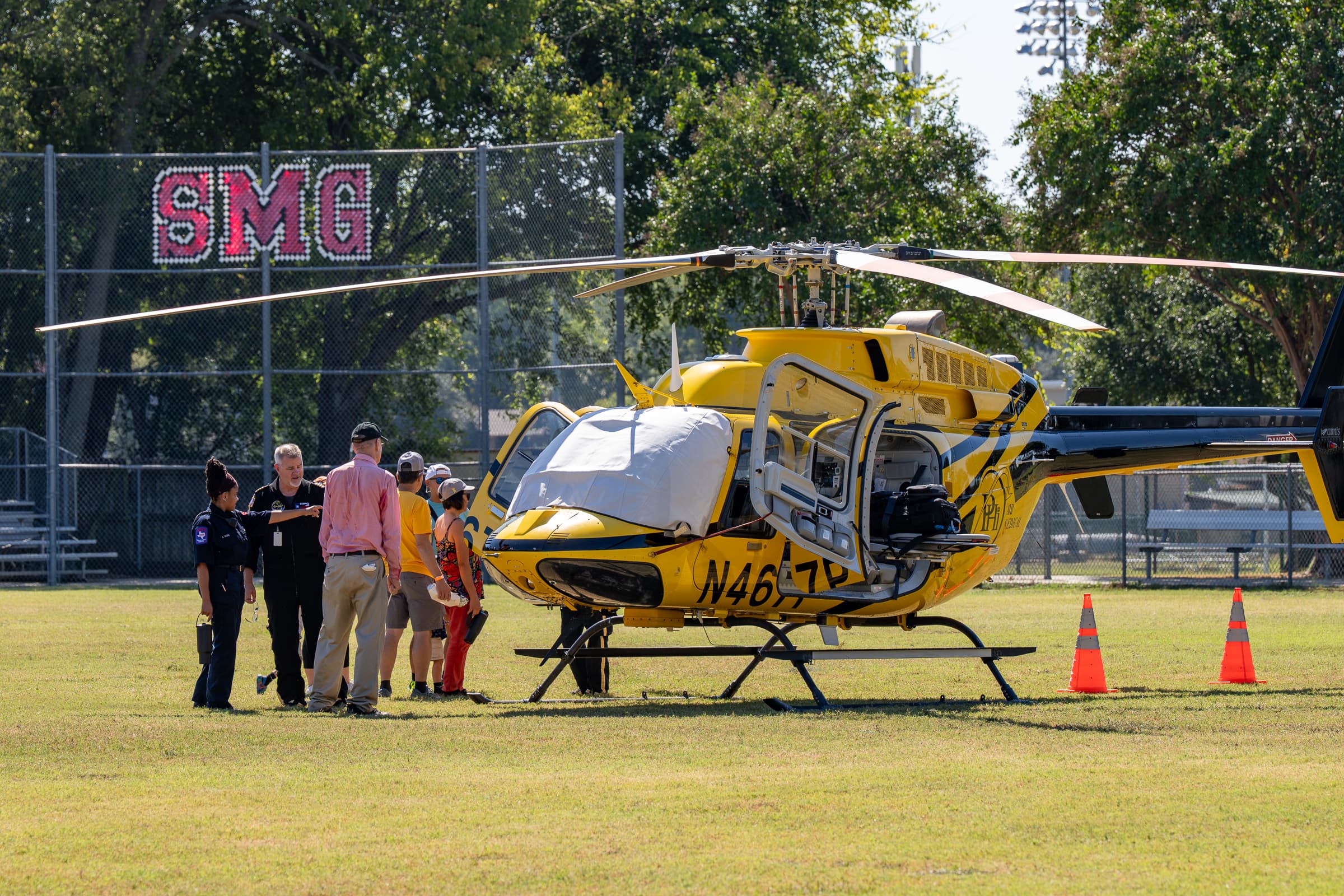 GorettiFest visitors exploring a yellow helicopter on the Saint Maria Goretti school field