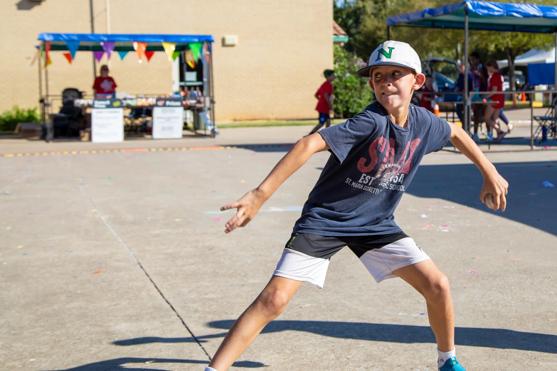 a young boy pitching a baseball in the GorettiFest games midway