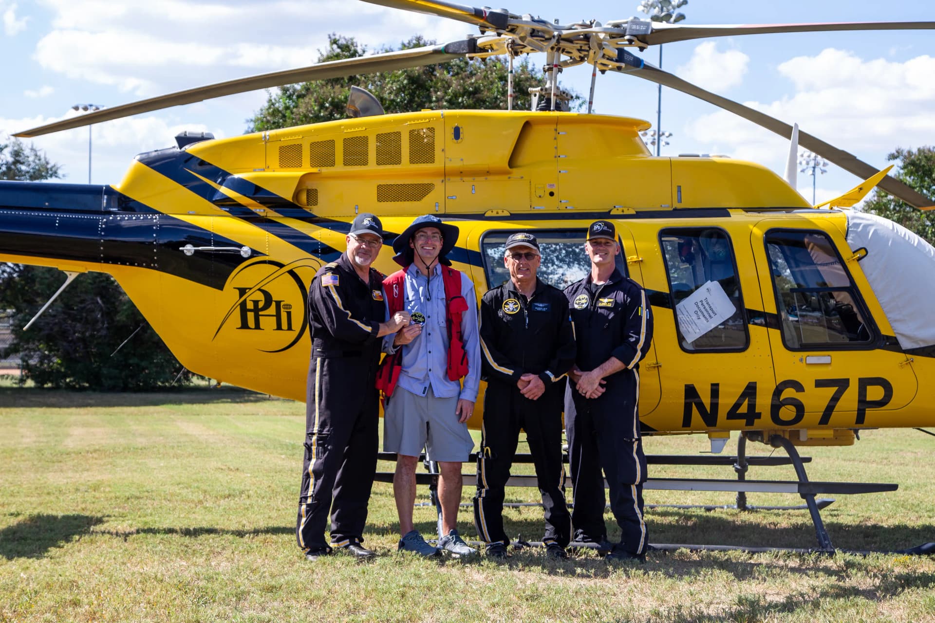 GorettiFest volunteers stand with helicopter crew in front of a helicopter at GorettiFest